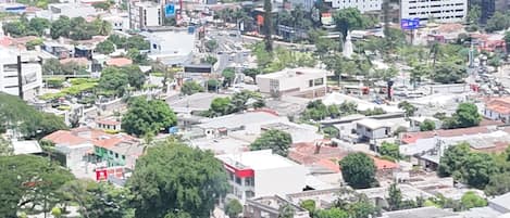 A cityscape with a prominent modern building in the foreground, surrounded by various other buildings and greenery.