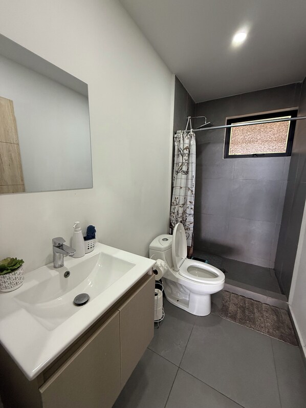 A modern bathroom with a white sink, a toilet, and a shower area.