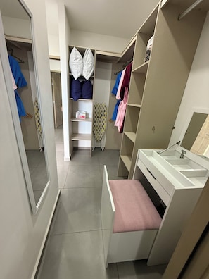 A walk-in closet with shelves, hanging space, and a vanity area.
