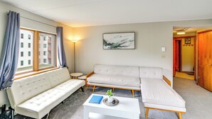 A modern living room with a sofa, a small table, a lamp, and a painting on the wall. - Snow Mountain Condo: Hot Tub + Shuttle to Resort (West Dover)