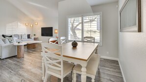 A modern living room with a dining area, featuring a wooden dining table, white chairs, and a grey sofa. - Hike & Golf! Cave Creek Retreat w/ Backyard Oasis (Cave Creek)
