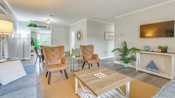 Een moderne woonkamer met een bank, twee leren fauteuils, een salontafel en een televisie aan een witte muur.