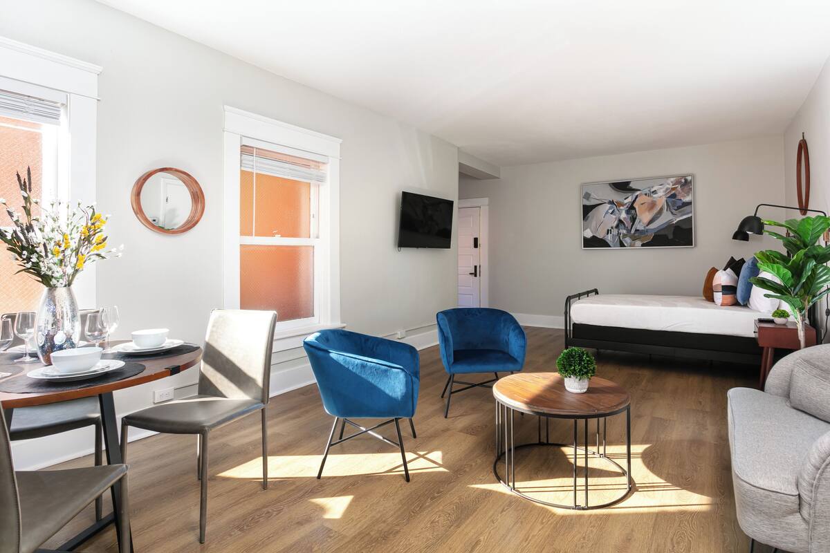 En moderne stue med spiseplads, en sofa, et sofabord og et fjernsyn.
