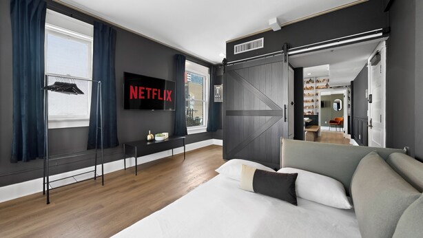 A modern bedroom with a large bed, a TV, and a view of the city.