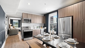 A modern kitchen with a dining area, stainless steel appliances, and a view of the city.
