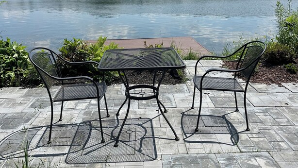 A patio with a table and chairs overlooking a lake. - Charming apartment on Main Street  (Lake Placid)
