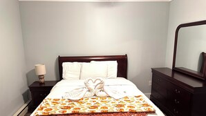A neatly made bed with a heart-shaped towel arrangement, a patterned throw blanket, and a bedside lamp. - Charming apartment on Main Street  (Lake Placid)