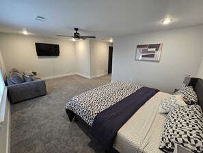 A bedroom with a bed, a sofa, a ceiling fan, a TV, and a framed picture on the wall. - Haven II Charming, Cozy getaway,Pool, WIFI (Princeton)