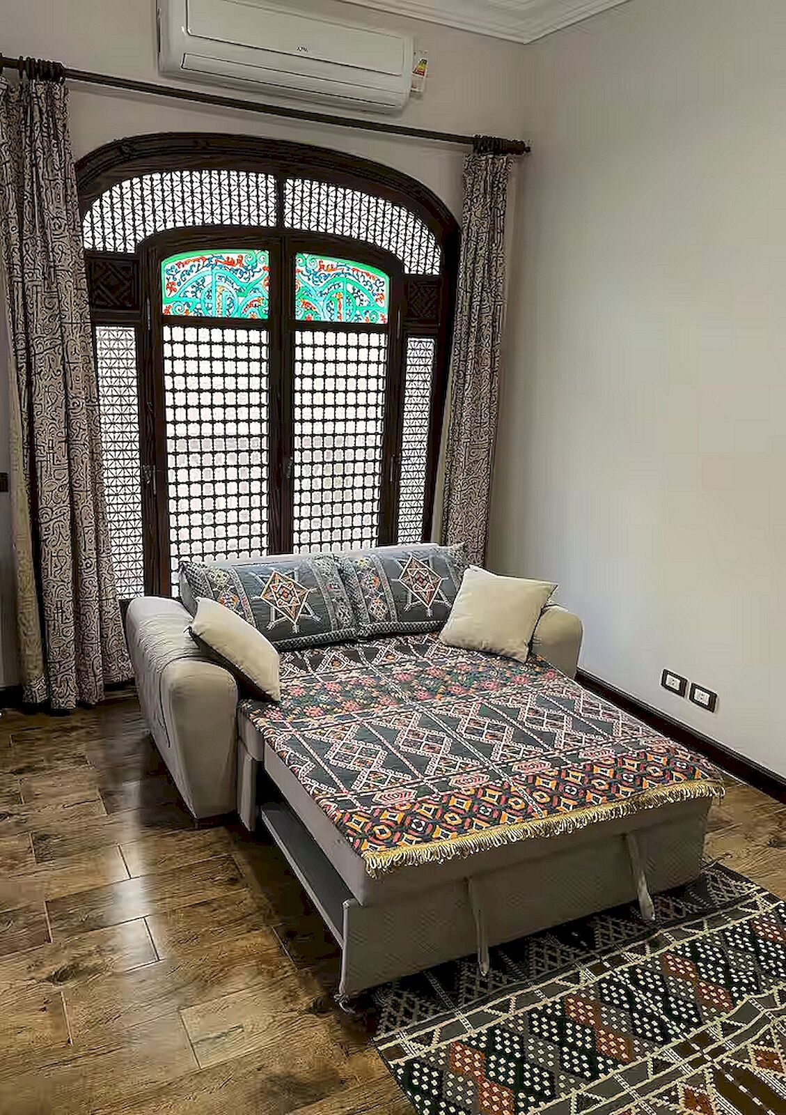 A room with a bed, curtains, and a patterned rug.
