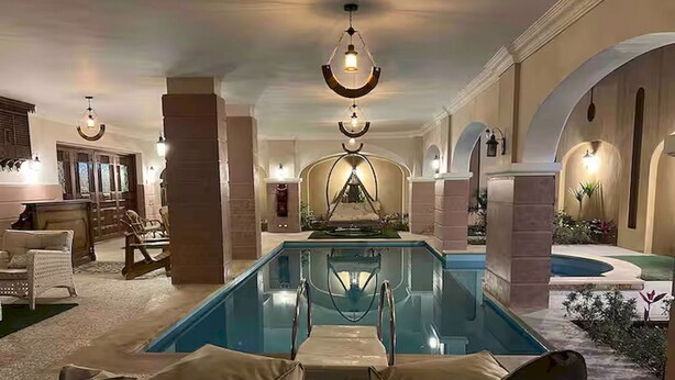 A pool area with lounge chairs, a bar, and a fountain. - Heritage valley. (New Cairo 1)