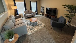 A living room with a sofa, armchairs, a coffee table, a TV, and a ceiling fan. - Spacious 4BR Boho - Family + Pet Friendly (Clarksville)