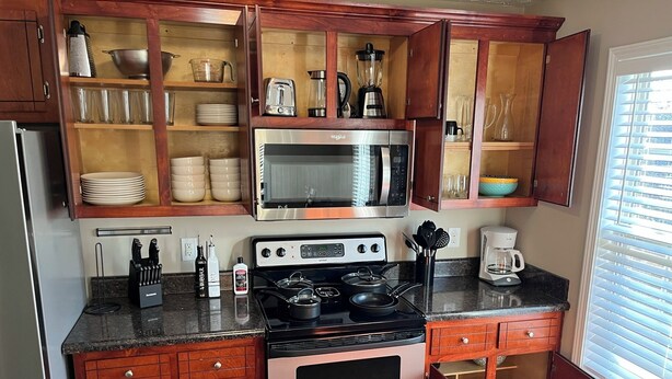 A kitchen with a built-in oven, microwave, and stove. There are wooden cabinets with glass doors, a coffee maker, and a kettle on the counter. - Spacious 4BR Boho - Family + Pet Friendly (Clarksville)