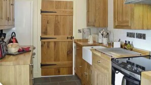 A kitchen with wooden cabinets, a stove, and a sink.