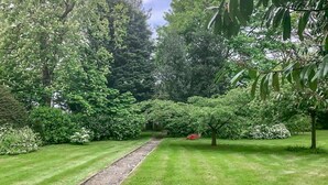A well-maintained garden with a central pathway, surrounded by lush greenery and trees. - Lovely home in Ingouville sur Mer (Ingouville sur Mer)