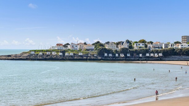 A coastal town with beachfront properties, clear skies, and a calm sea.