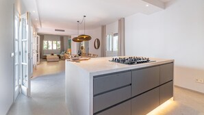 A modern kitchen with a central island, pendant lighting, and a view into the living area. - Beautiful home in Canyamel with private swimming pool, can be inside or outside (Canyamel)