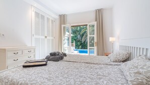 A bedroom with a large bed, a dresser, and a view of a swimming pool through an open door. - Beautiful home in Canyamel with private swimming pool, can be inside or outside (Canyamel)