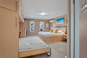 Ein modernes Schlafzimmer mit zwei Betten, einem Nachttisch und einem Fenster mit Jalousien.