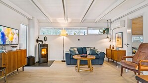 En moderne stue med pejs, sofa, sofabord og tv.