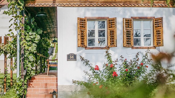 Un bâtiment blanc avec deux fenêtres, un escalier en briques et une enseigne portant le numéro « 54 ».
