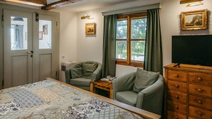 Une chambre à coucher avec un lit, deux fauteuils, une commode, une fenêtre avec des rideaux et un tableau au mur.
