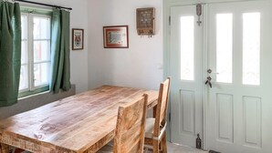 Une table à manger en bois avec des chaises, une porte avec un trou de serrure et une fenêtre avec des rideaux.