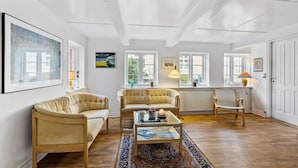 A spacious living room with a wooden floor, two cream-colored sofas, a glass coffee table, and a patterned rug. - 3 bedroom awesome home in Marstal (Marstal)