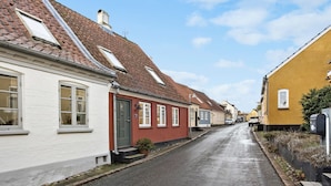 A narrow street lined with traditional houses, featuring steeply pitched roofs and a mix of white and yellow facades. - 3 bedroom awesome home in Marstal (Marstal)