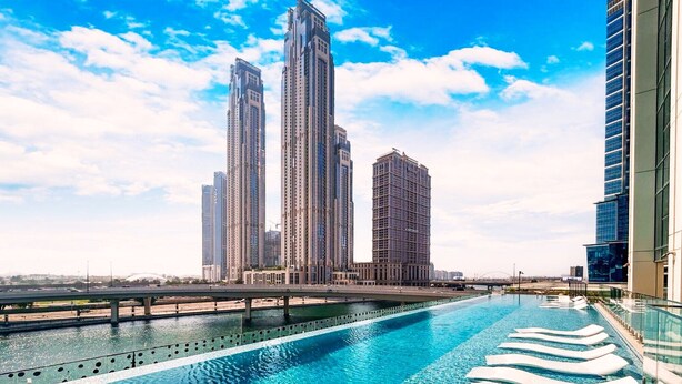 A swimming pool with lounge chairs, surrounded by high-rise buildings. - Vibrant 2BR, Miami Vibes at Business Bay (Dubai)
