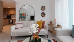 A modern living room with a sofa, coffee table, and a dining area with a table and chairs. - Vibrant 2BR, Miami Vibes at Business Bay (Dubai)