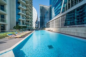 A modern hotel with a swimming pool, high-rise buildings, and a clear sky. - Vibrant 2BR, Miami Vibes at Business Bay (Dubai)