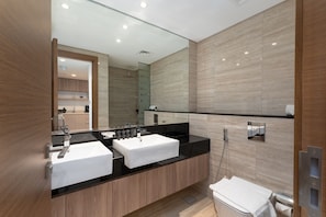 Ein modernes Badezimmer mit einem Doppelwaschbecken, einer Duschkabine aus Glas und einem großen Spiegel.