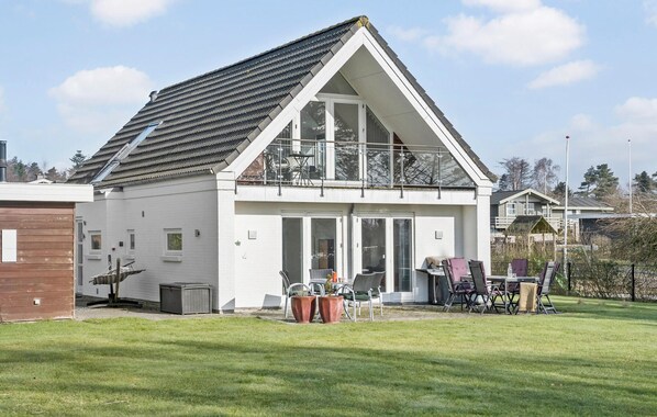 A modern two-story house with a sloped roof, large windows, and a balcony.