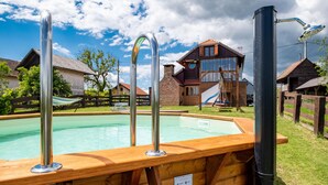A wooden pool with metal ladders, surrounded by a wooden deck and a picnic table. - Cozy home in Klostar Ivanic with sauna (Klostar Ivanic)
