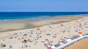 A beach with numerous sunbeds and umbrellas, a long stretch of beach chairs, and a clear view of the ocean. - Cozy apartment in Oostende with WiFi (Oostende)
