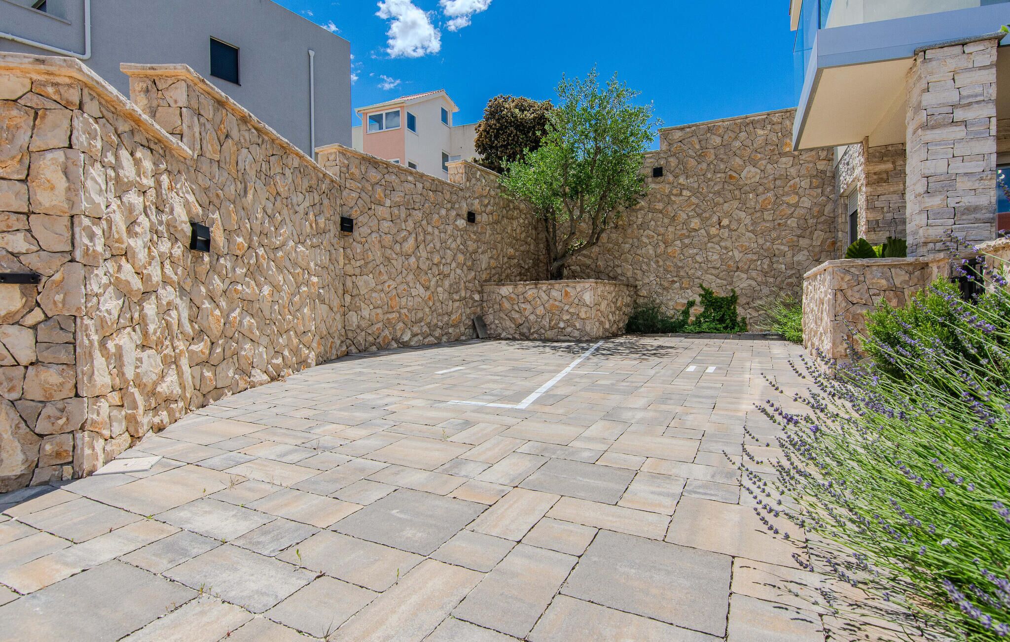 A courtyard with stone walls and a paved area, surrounded by buildings.