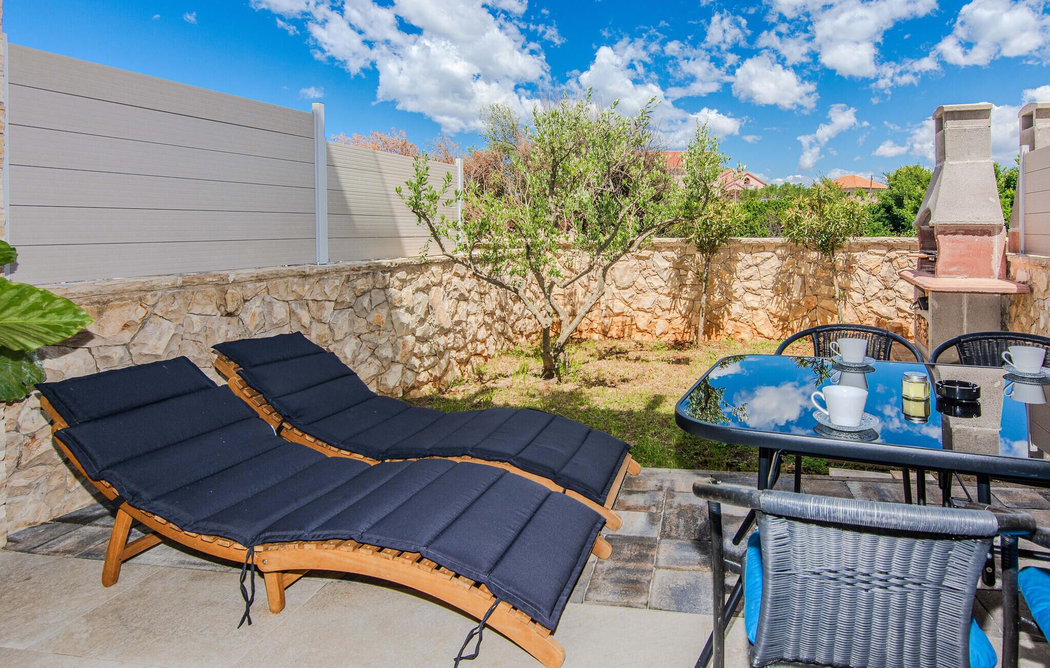 Eine Terrasse mit zwei Liegestühlen, einem Tisch mit Tasse und Untertasse sowie einer Steinmauer.