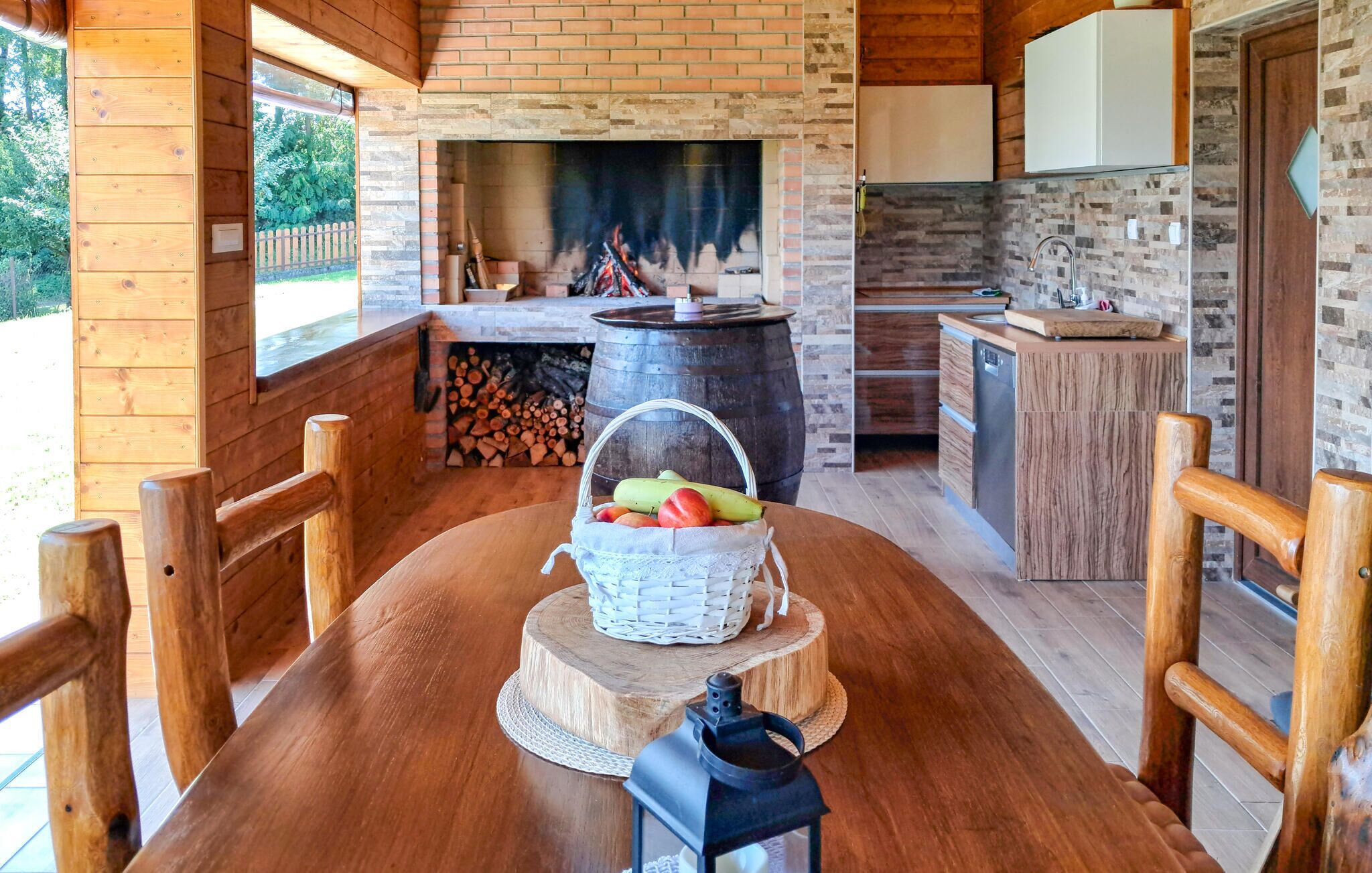 A wooden dining table with a basket of fruit, a lantern, and a fireplace in the background.