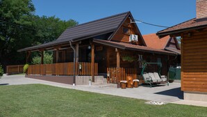 Een houten hut met een overdekte veranda, een omheinde tuin en buitenmeubels.