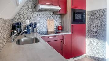 A compact kitchen with a sink, a microwave, and red cabinets.