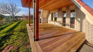 A modern house with a wooden deck, brick walls, and large windows.