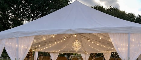 A tented wedding venue with a central aisle, tables, and chairs arranged for guests.