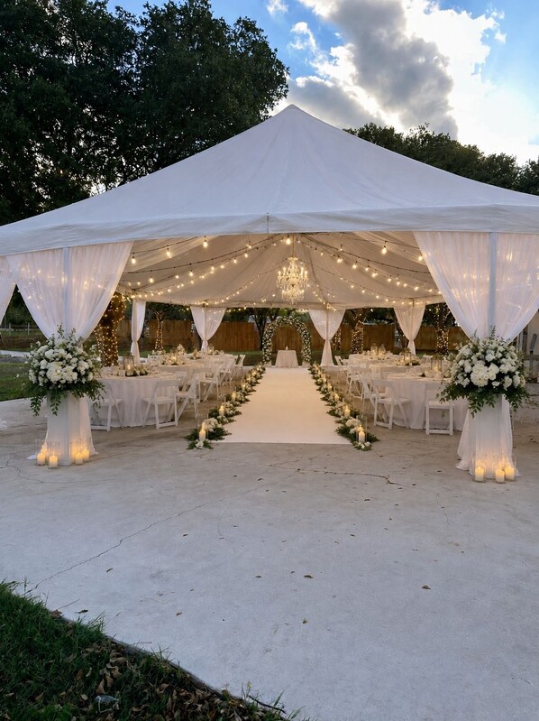 Un salón de bodas con carpas, un pasillo central, mesas y sillas dispuestas para los invitados.