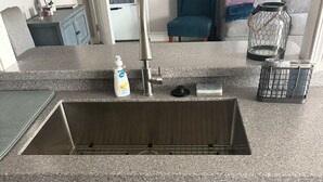Una cocina con un lavamanos de acero inoxidable, un grifo y un dispensador de jabón en la encimera.