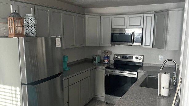 Una cocina moderna con electrodomésticos de acero inoxidable, encimera de granito y muebles de cocina en tonos claros.