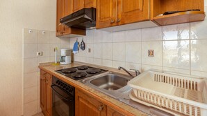 Une cuisine avec des meubles de rangement en bois, une cuisinière, un évier et un égouttoir à vaisselle.