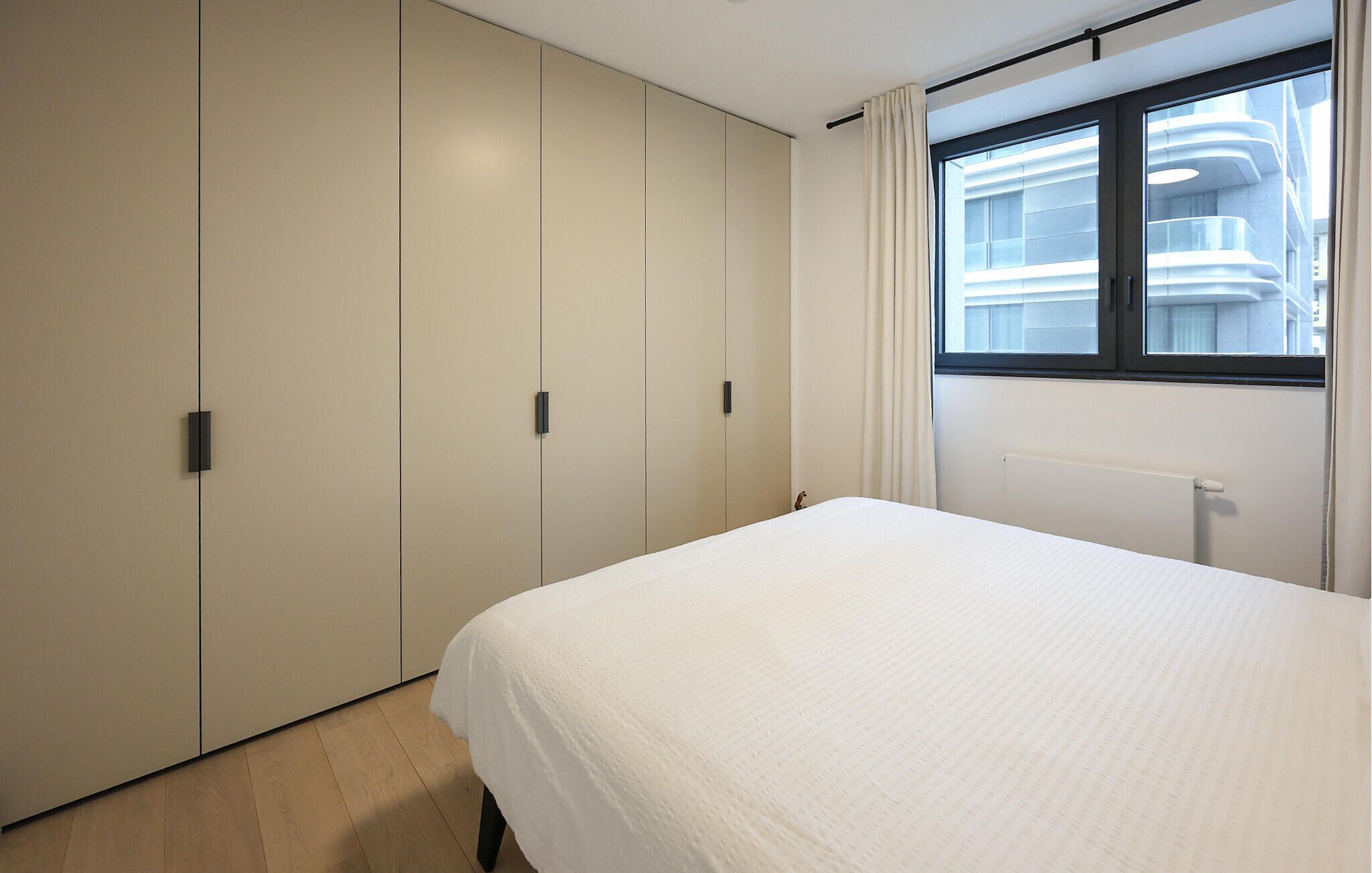Una camera da letto con un letto, una finestra con tende e un armadio.