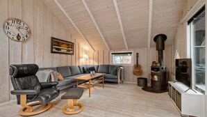 A cozy wooden interior with a sofa, leather chair, wooden coffee table, and a fireplace. - Gorgeous home in Oksbøl with sauna (Oksbøl)