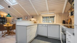A modern kitchen with white cabinetry, a built-in dishwasher, a window with a view, and a skylight above. - Gorgeous home in Oksbøl with sauna (Oksbøl)