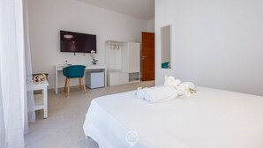 Ein modernes Hotelzimmer mit einem Bett, einem Schreibtisch, einem Sessel, einem Fernseher und einem Kleiderschrank.